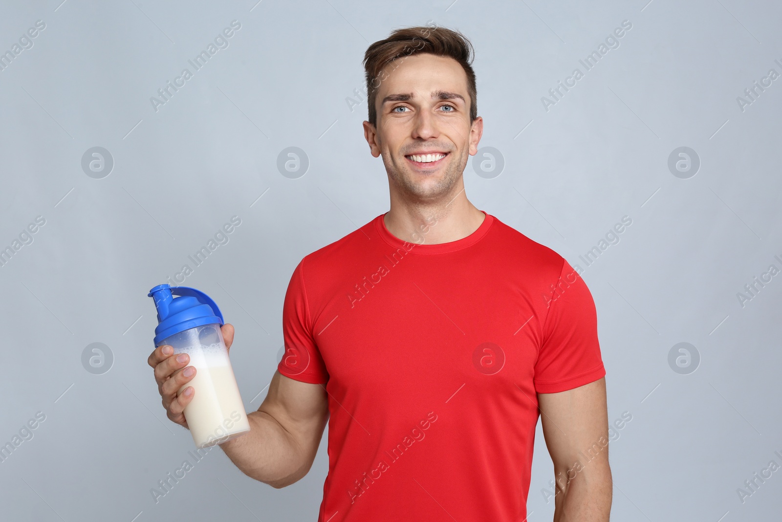 Photo of Portrait of man with bottle of protein shake on color background