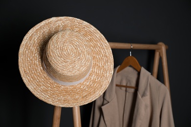 Stylish straw hat on clothing rack indoors