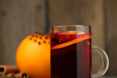 Aromatic mulled wine in glass cup on blurred background, closeup. Space for text