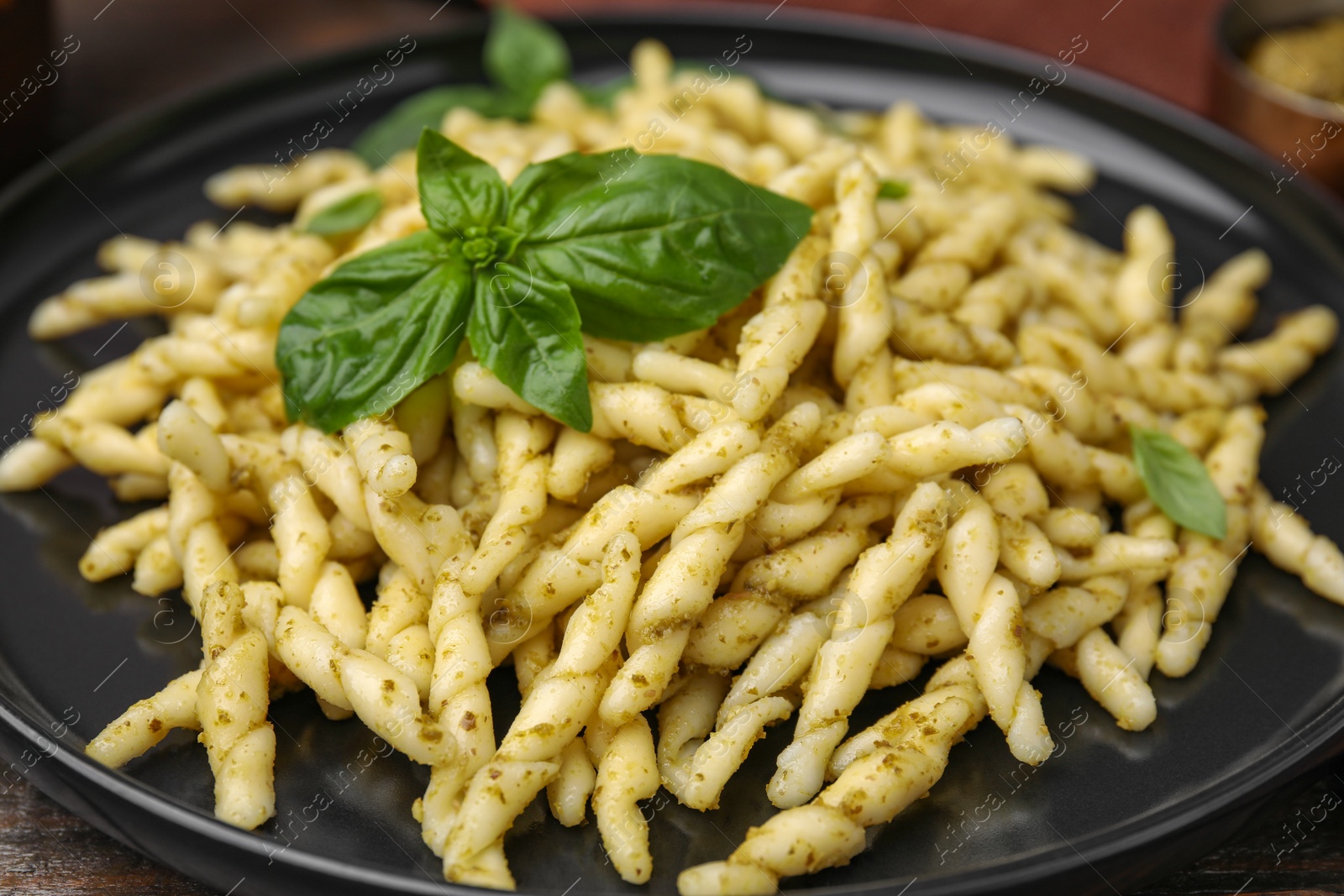 Photo of Plate of delicious trofie pasta with pesto sauce and basil leaves on table, closeup