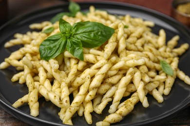 Plate of delicious trofie pasta with pesto sauce and basil leaves on table, closeup