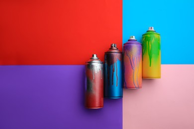 Photo of Used cans of spray paints on color background, flat lay. Graffiti supplies