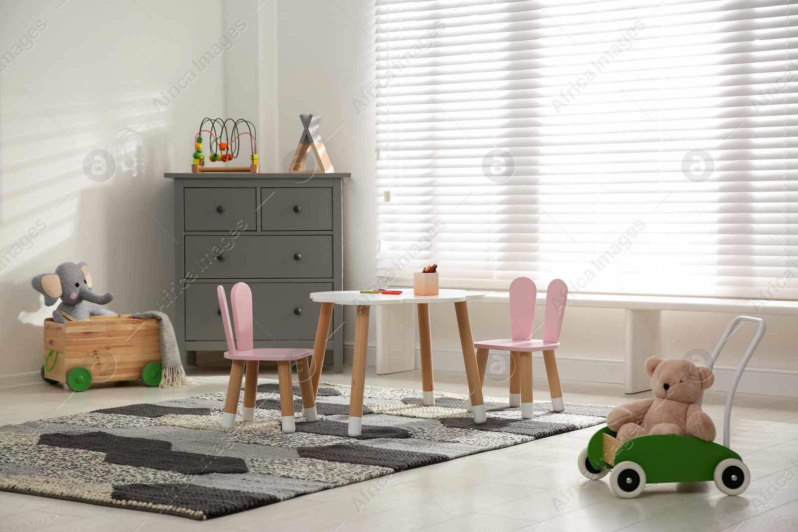 Photo of Little table and chairs with bunny ears in children's room. Interior design