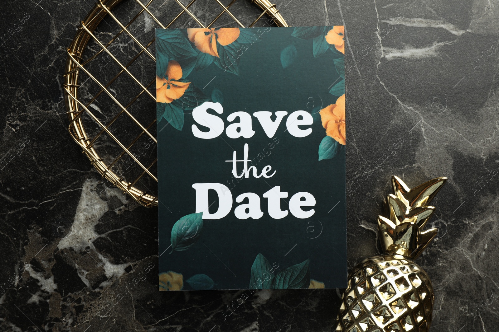 Photo of Beautiful card with Save the Date phrase and decor elements on black marble background, flat lay