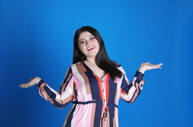 Beautiful overweight woman posing on blue background. Plus size model