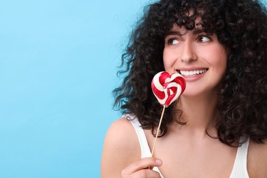 Photo of Beautiful woman with lollipop on light blue background, space for text