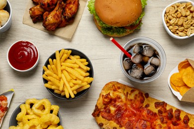 Photo of French fries, onion rings and other fast food on white wooden table, flat lay