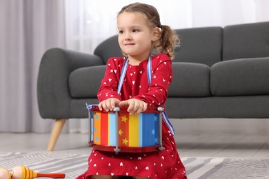 Photo of Little girl playing toy drum at home