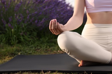 Woman practicing yoga on exercise mat in lavender field, closeup. Space for text