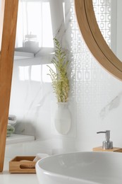 Photo of Silicone vase with flowers on white marble wall over countertop in stylish bathroom