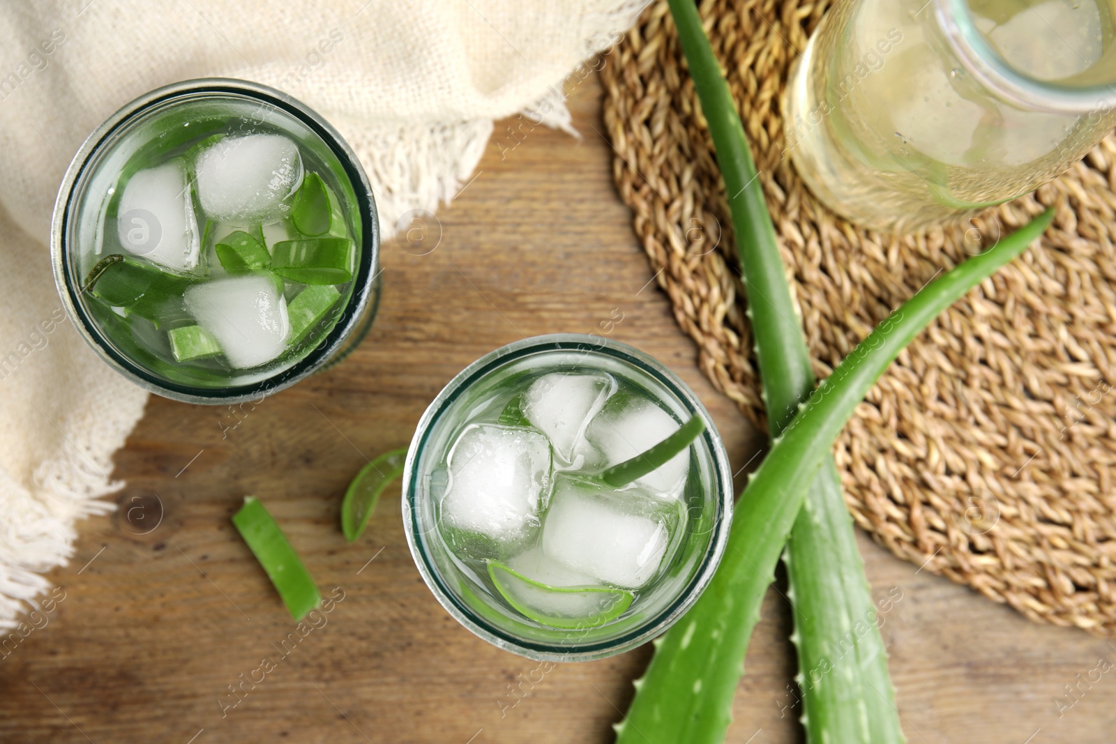 Photo of Fresh aloe drink with ice cubes on wooden table, flat lay