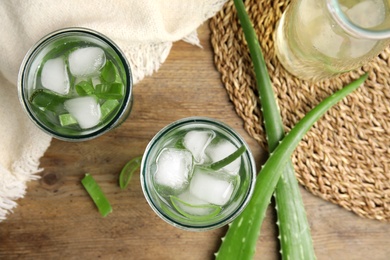 Photo of Fresh aloe drink with ice cubes on wooden table, flat lay