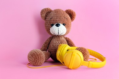 Photo of Baby songs. Toy bear and yellow headphones on pink background
