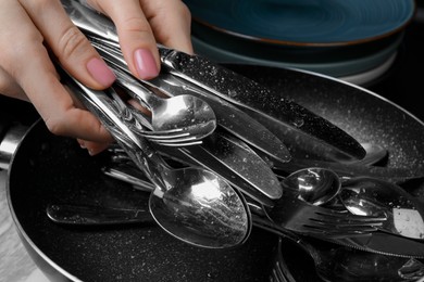 Woman holding clean silver kitchenware on white marble table, closeup