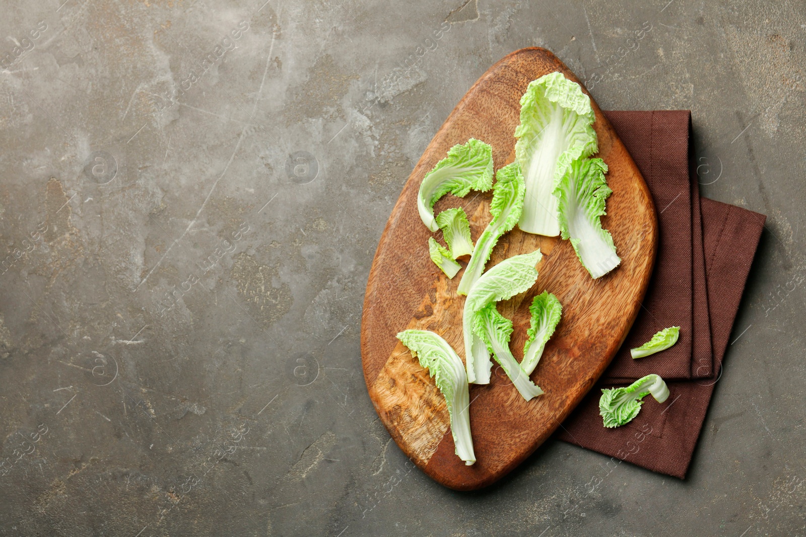 Photo of Pieces of fresh Chinese cabbage on gray textured table, top view. Space for text