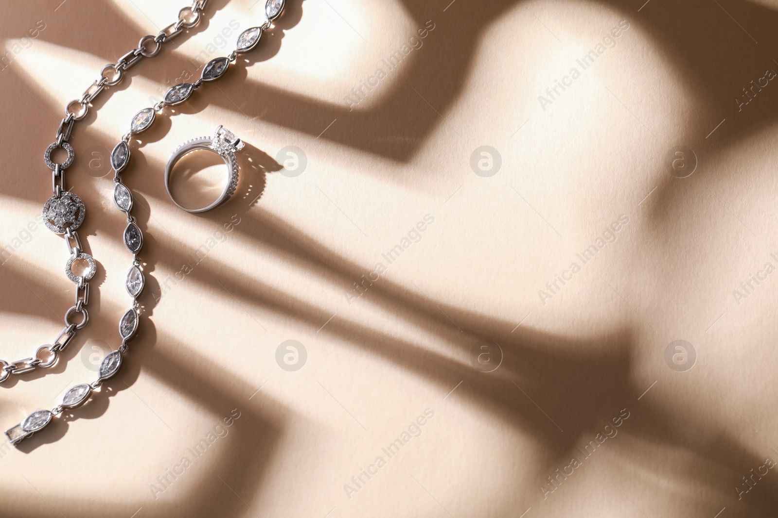 Photo of Luxury jewelry. Elegant bracelets and ring on beige background, flat lay with space for text