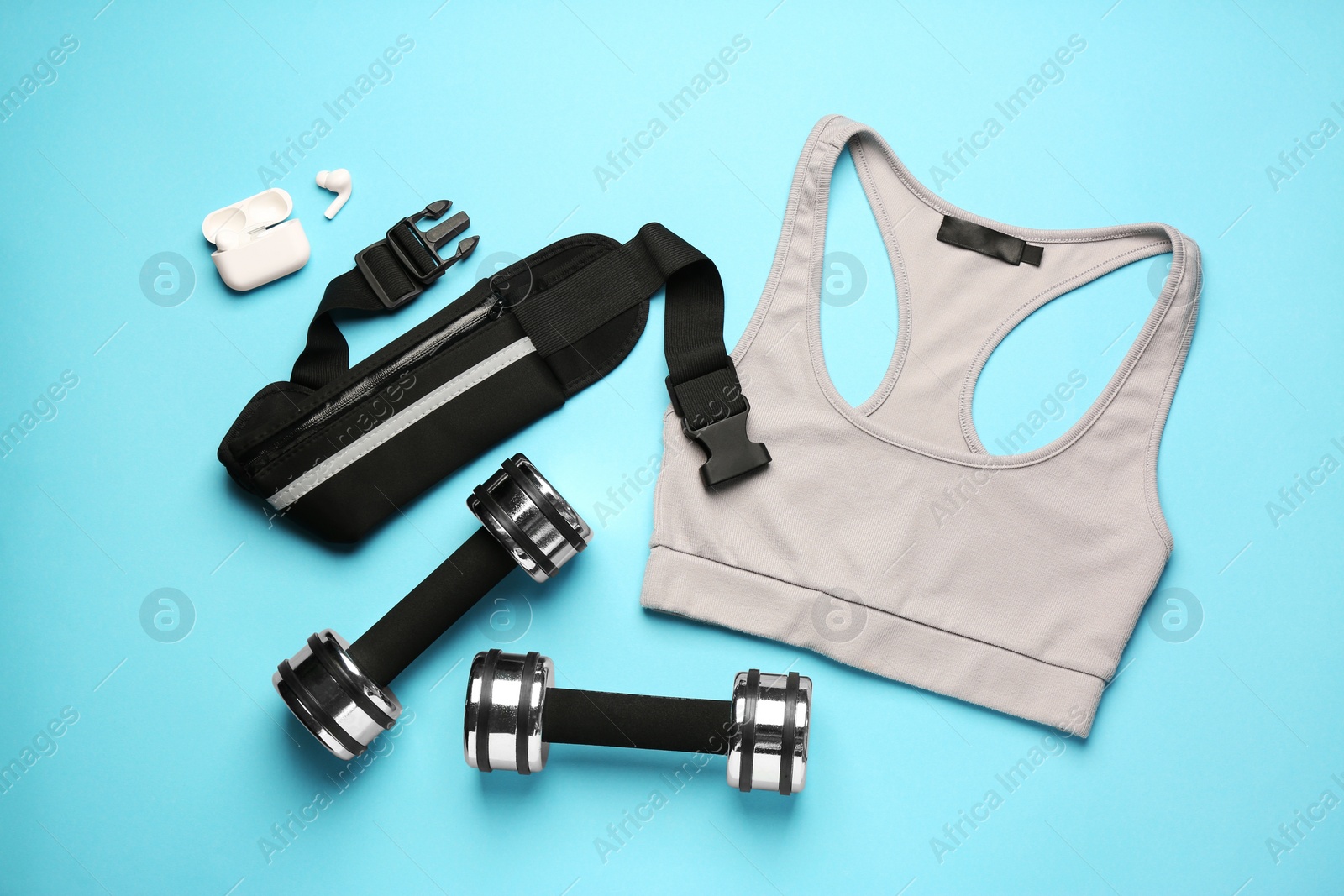 Photo of Flat lay composition with stylish black waist bag on light blue background