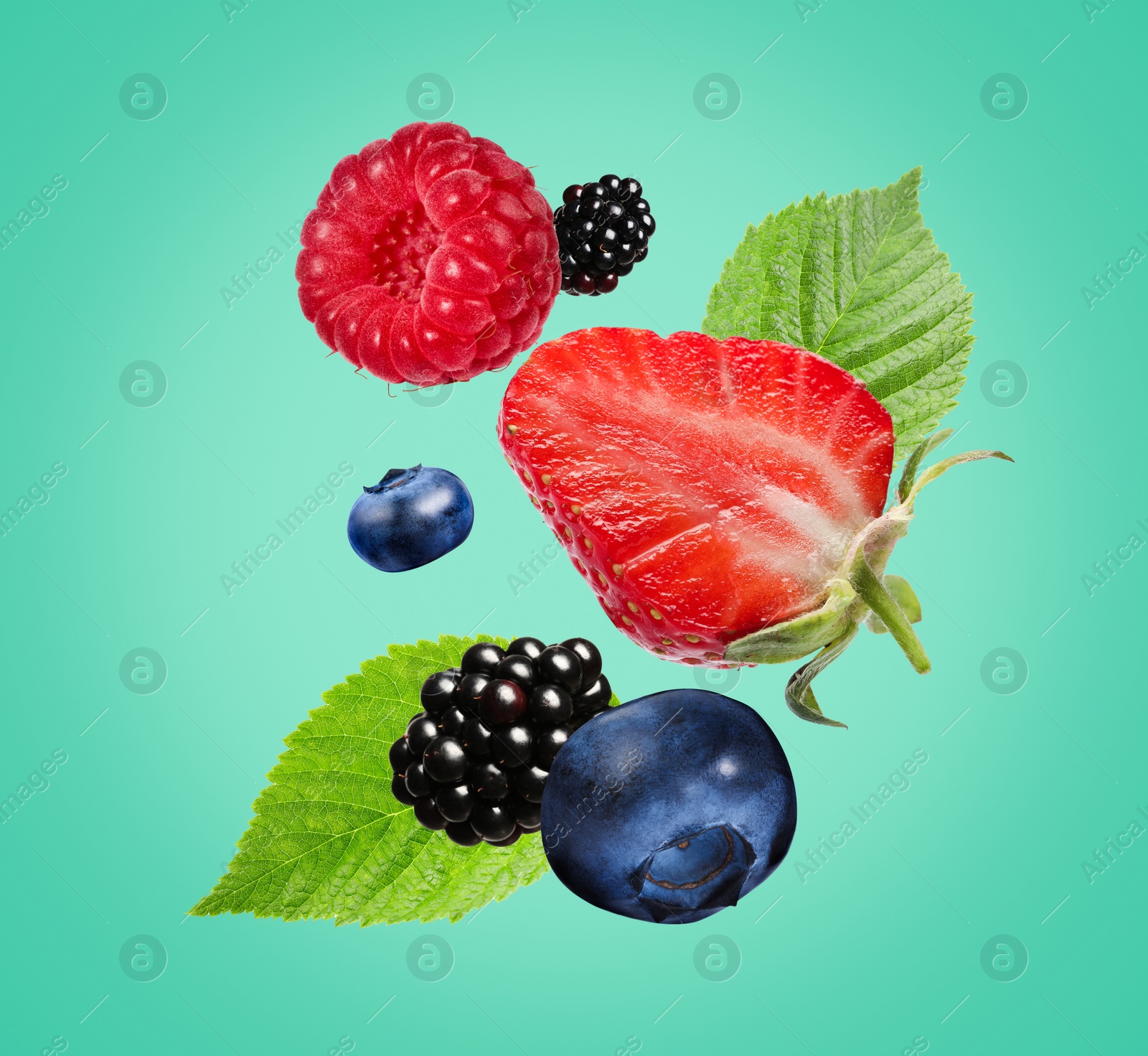 Image of Many different fresh berries falling on turquoise background