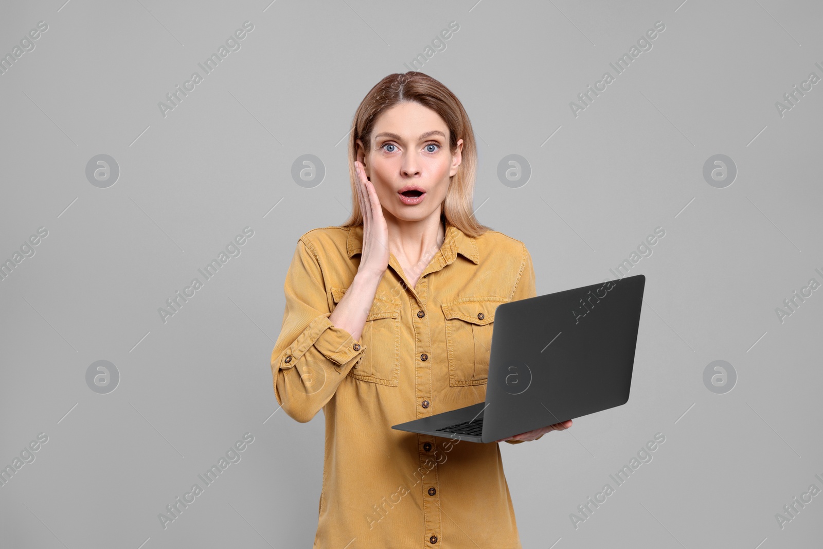 Photo of Emotional woman with laptop on light grey background