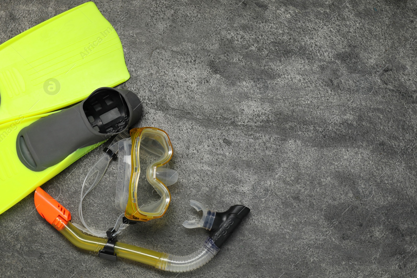 Photo of Sports equipment. Flippers, diving mask and snorkel on grey textured table, flat lay. Space for text