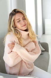 Photo of Beautiful young woman wearing warm pink sweater at home