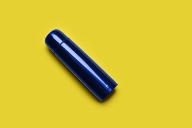 Photo of Blue metal thermos on yellow background, top view. Space for text