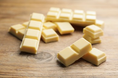 Pieces of tasty sweet chocolate on wooden table, closeup