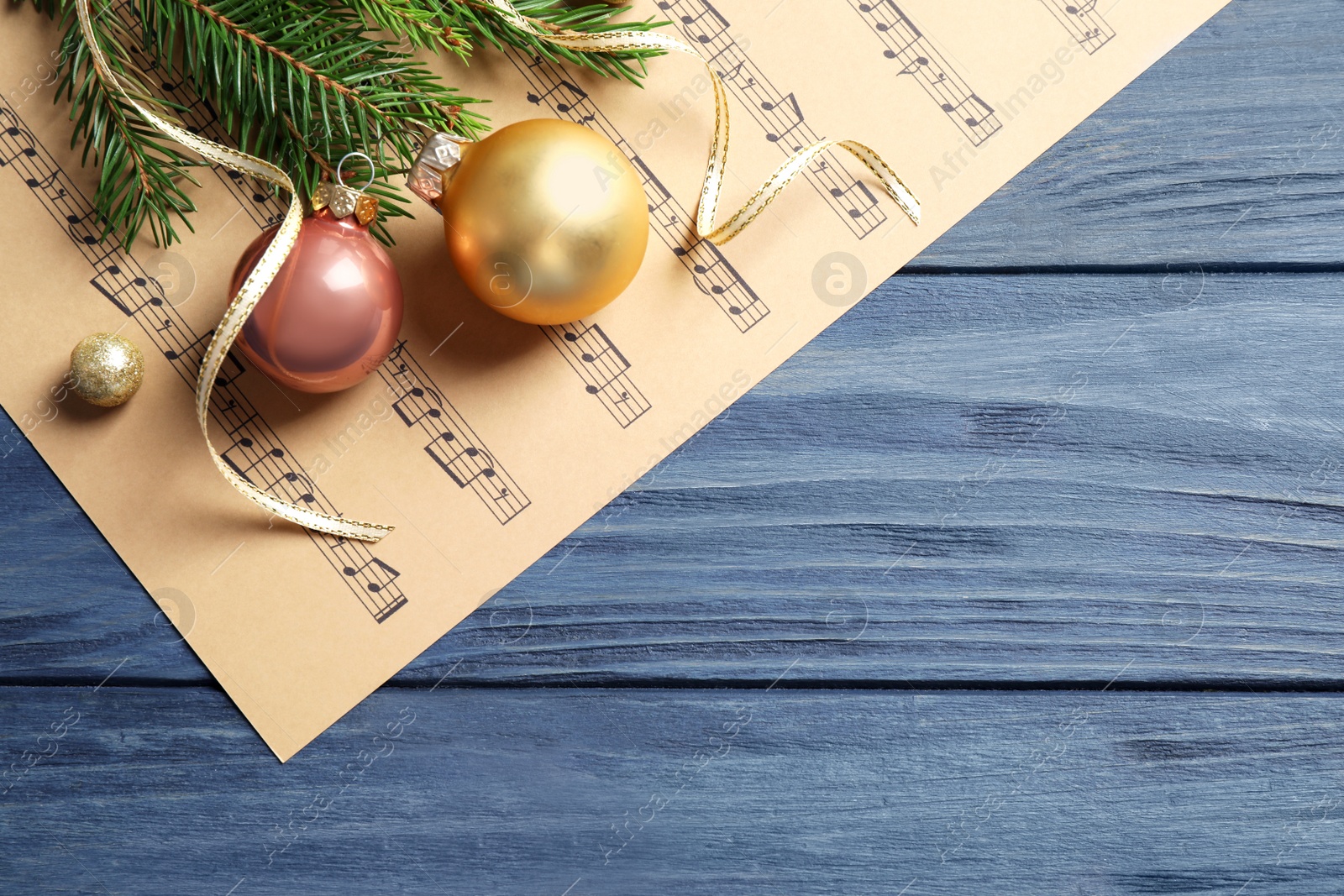 Photo of Flat lay composition with Christmas decorations and music sheets on blue wooden table. Space for text