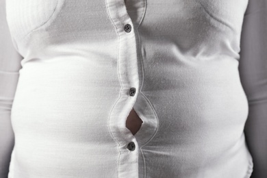 Photo of Overweight woman in tight shirt, closeup. Obesity and weight loss