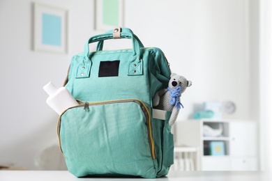 Photo of Maternity backpack with baby accessories on table indoors