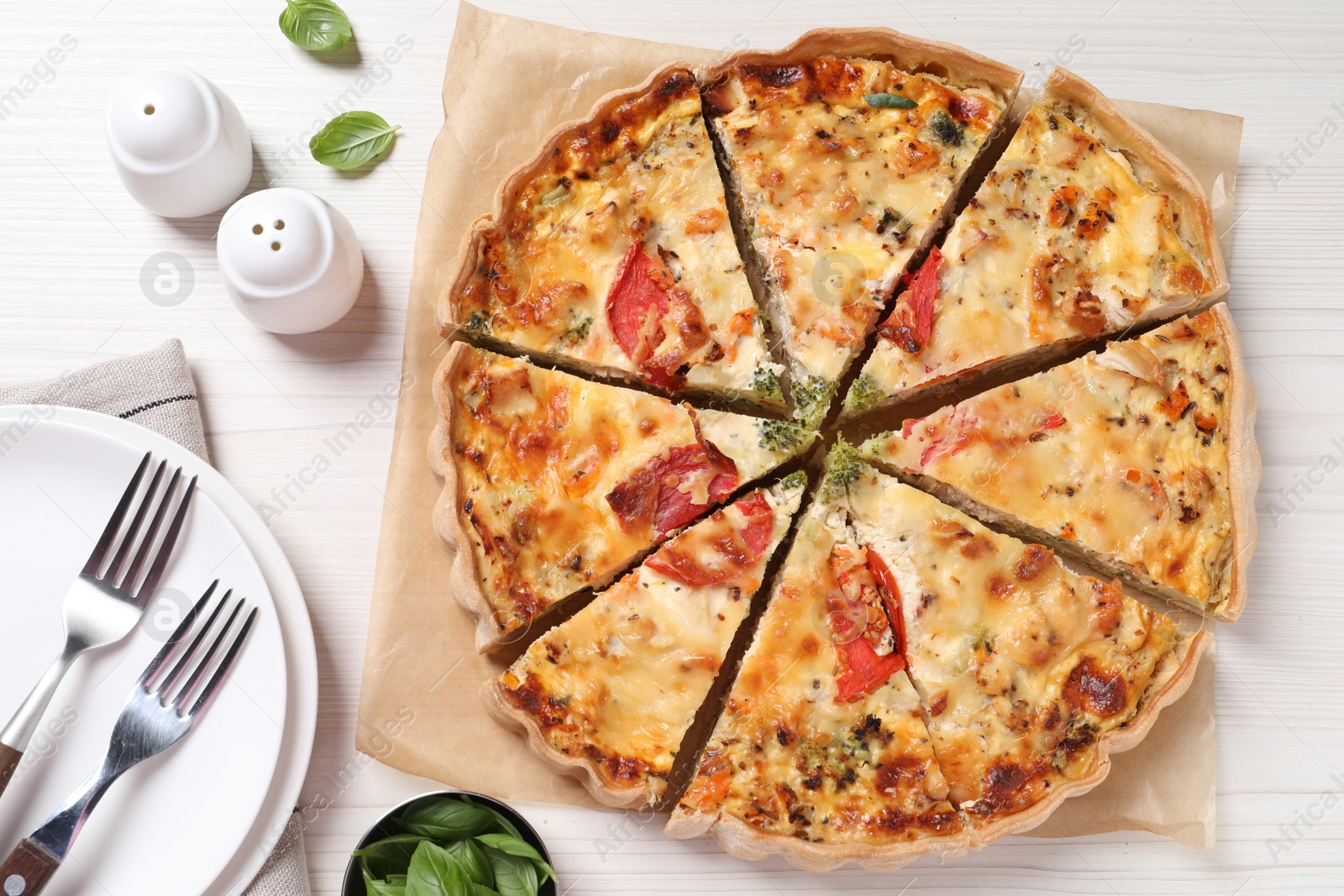 Photo of Tasty quiche with tomatoes and cheese served on white wooden table, flat lay