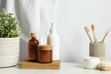 Photo of Different bath accessories and personal care products on light marble table against white wall