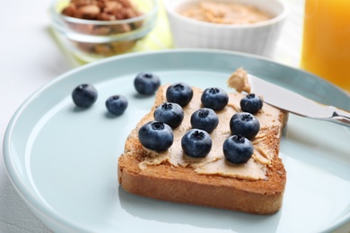 Photo of Toast with peanut butter and blueberries on white table, closeup. Healthy breakfast