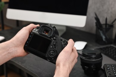 Photo of Photographer holding camera at dark table, closeup