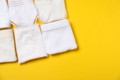Photo of Stylish folded women's underwear on yellow background, flat lay. Space for text
