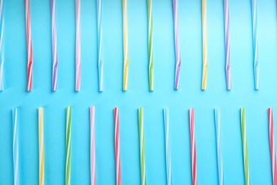 Photo of Colorful plastic drinking straws on light blue background, flat lay