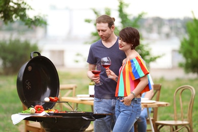 Young people having barbecue with modern grill outdoors