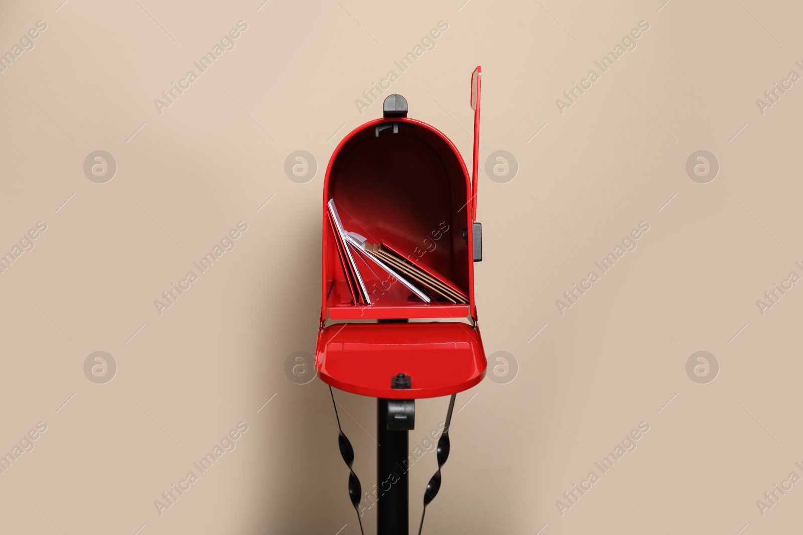 Photo of Open red letter box with envelopes against beige background