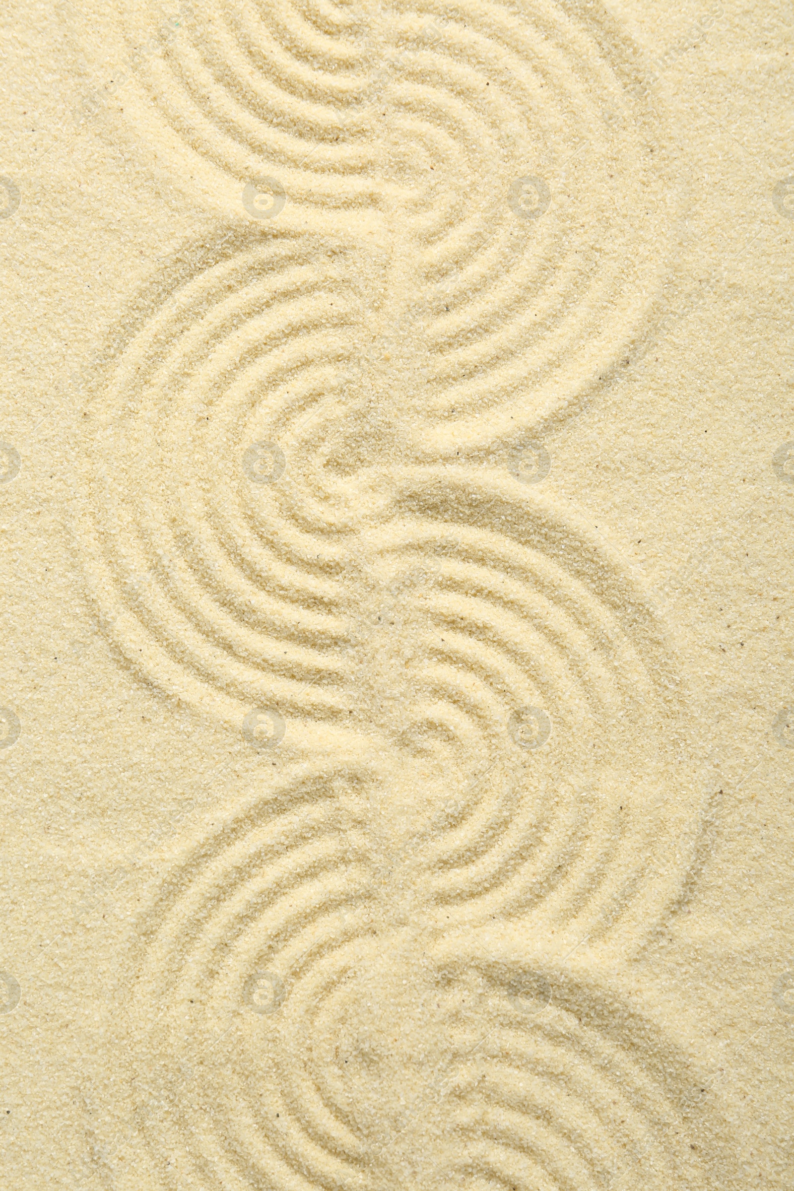 Photo of Zen rock garden. Wave pattern on beige sand, top view