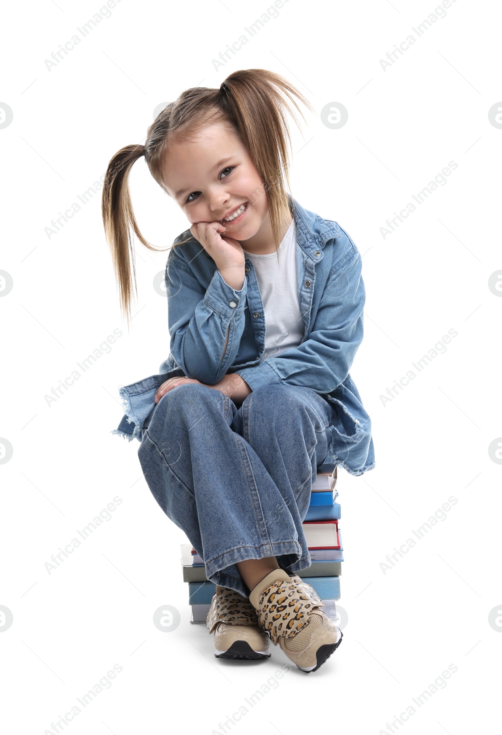 Photo of Cute little girl sitting on stack of books against white background