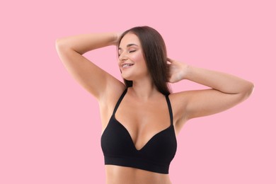 Photo of Portrait of young woman with beautiful breast on pink background