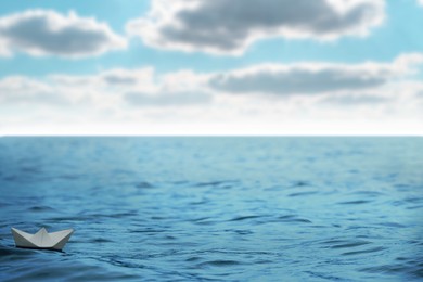 Image of White paper boat floating on calm sea. Space for text