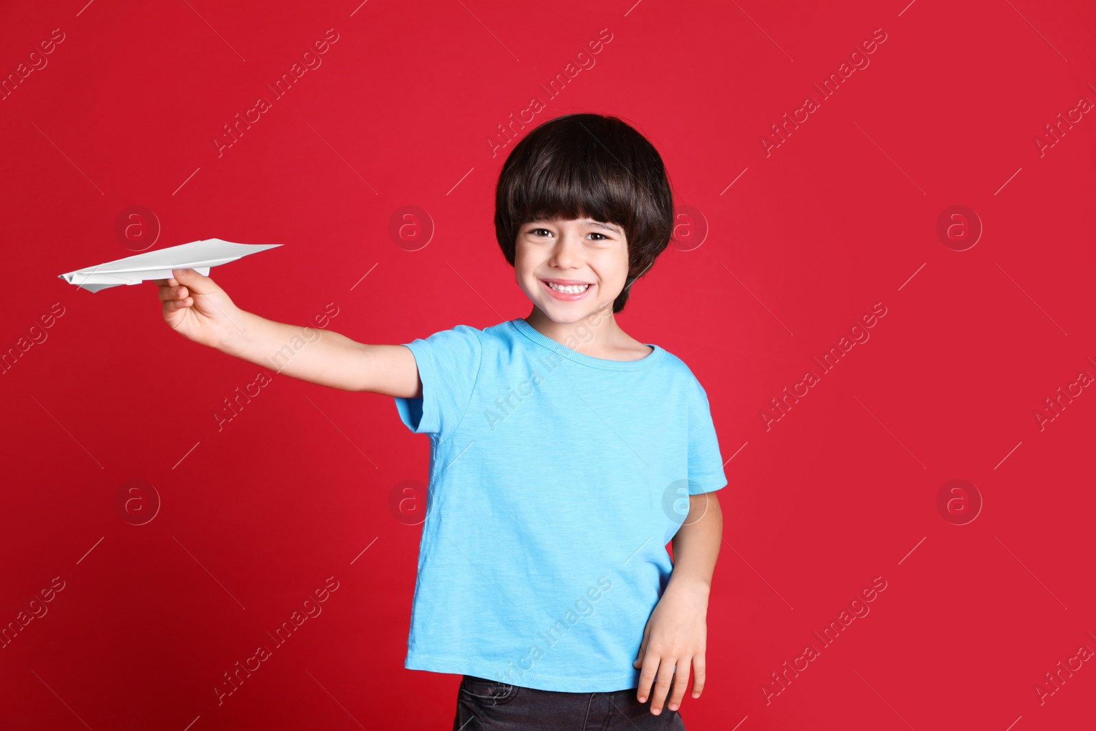 Photo of Cute little boy with paper plane on red background