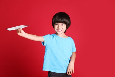 Cute little boy with paper plane on red background