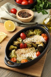 Photo of Tasty cod cooked with vegetables on wooden table