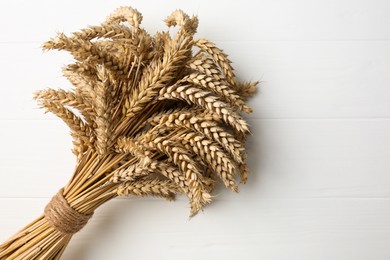 Bunch of wheat on white wooden table, top view. Space for text