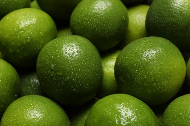 Photo of Fresh ripe limes with water drops as background, closeup