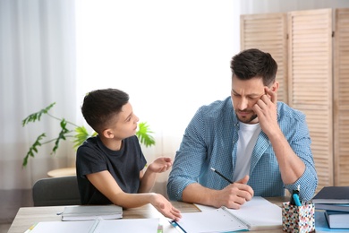 Dad helping his son with homework in room