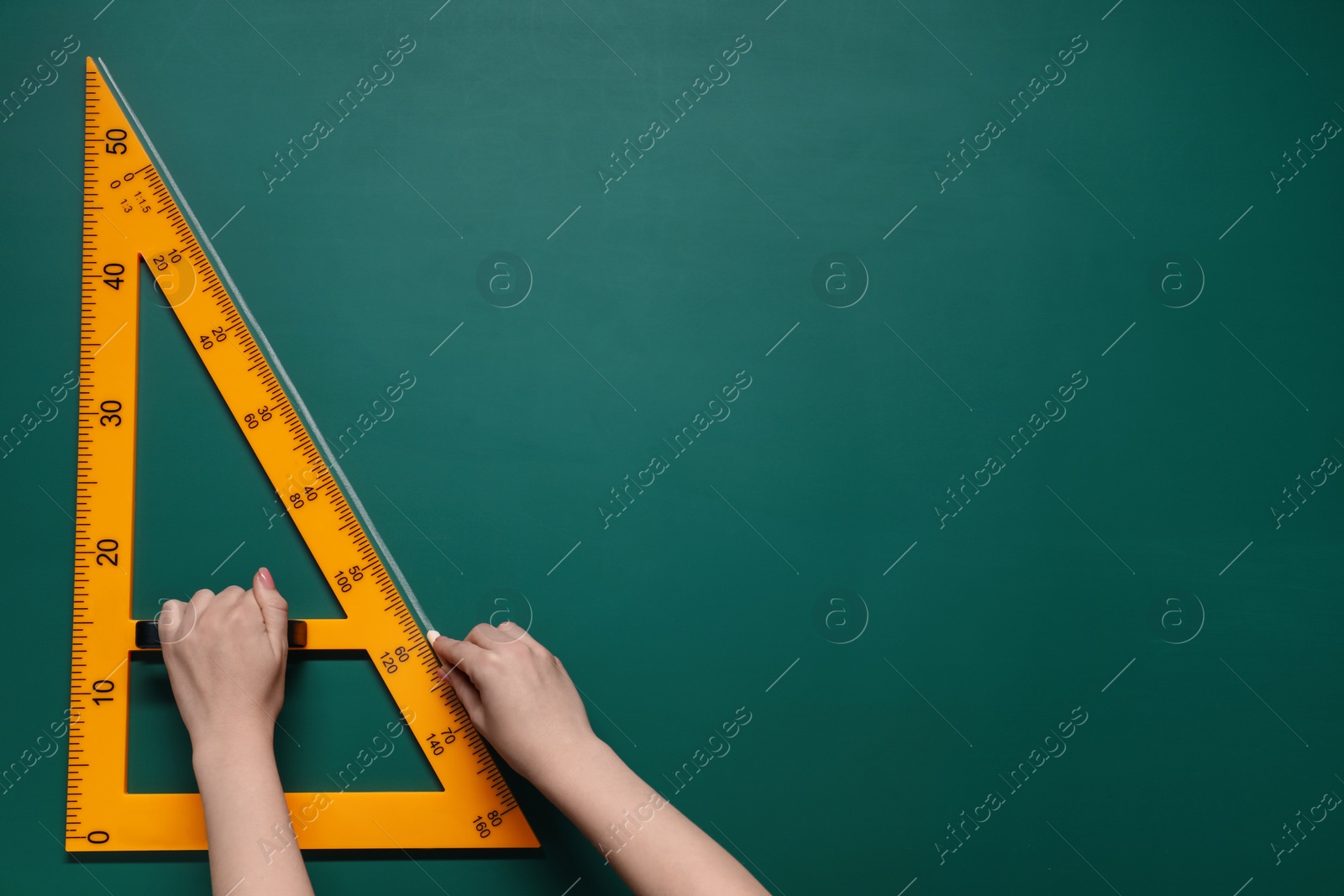 Photo of Woman drawing with chalk and triangle ruler on green board, closeup. Space for text