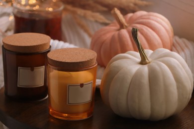 Beautiful pumpkins and scented candles on window sill indoors